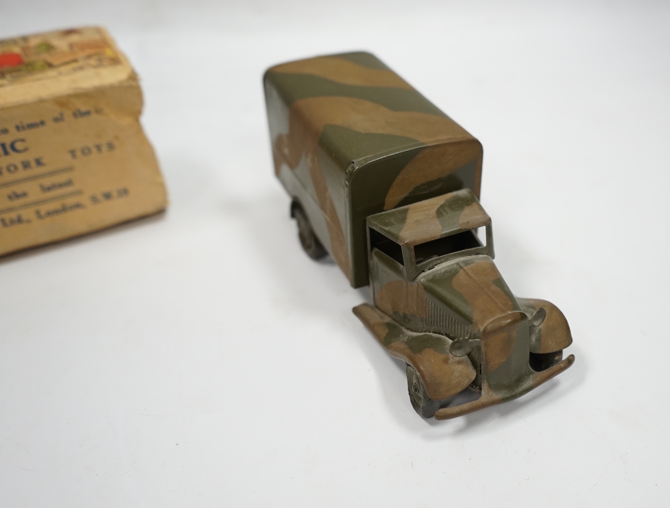 A Tri-ang Minic clockwork tinplate army lorry, in camouflage paint work, together with the remains of its box. Condition fair, original tires fatigued as expected, the box with missing flaps.